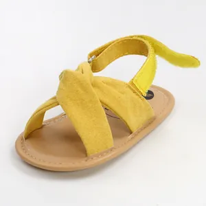 Vista de detalle de sandalias amarillas para bebé con correas cruzadas y velcro