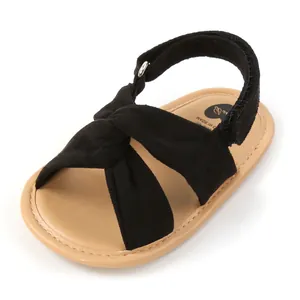 Primer plano de sandalias de gamuza negra para bebé con tiras cruzadas y cierre de velcro
