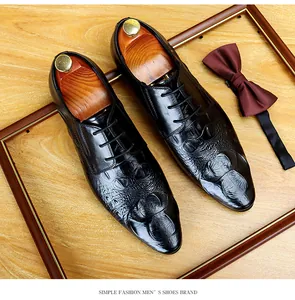 Dettaglio scarpe eleganti da uomo in pelle nera con motivo a coccodrillo e stringate