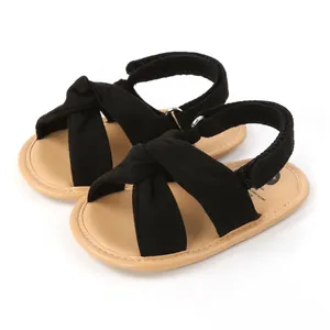 Sandalias negras para bebé con tiras cruzadas, suela blanda y cierre de velcro.