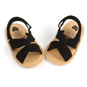 Detalle de sandalias para bebé con lazo negro y plantilla beige suave.