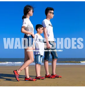 Gezin draagt oranje waterschoenen op een zonnig strand om te zwemmen en te snorkelen