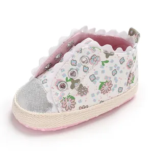Detailed view of floral print and scalloped lace trim on baby girl's soft-sole shoe
