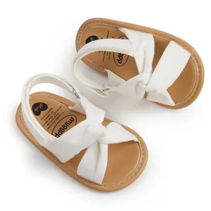Primer plano de sandalias blancas para bebé con tiras cruzadas y suelas marrones
