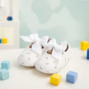 Detailansicht weißer Baby Mädchen Mary Jane Schuhe mit Blumenmuster und großen weißen Schleifen