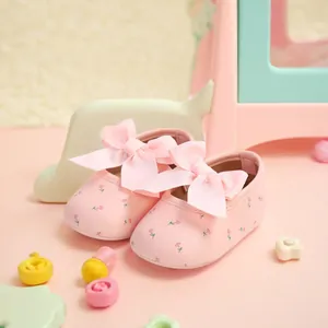 Nahaufnahme von rosa Baby-Prinzessinenschuhen mit Schleifenbändern und Blumenmustern
