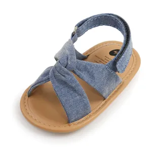 Vista detallada de sandalia para bebé en denim azul con diseño de nudo cruzado elegante.