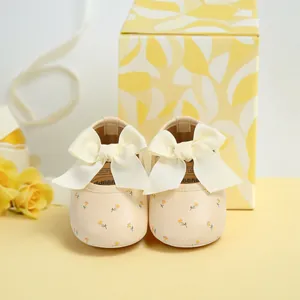 Detailansicht von cremefarbenen Baby-Lauflernschuhen mit Blumendruck und Schleife