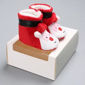 Detailed view of red plush baby Santa Claus boots presented on a white gift box prop