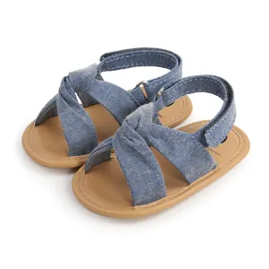 Detalle de sandalias de mezclilla para bebé con diseño de nudo cruzado y velcro