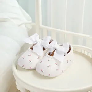 Detailaufnahme der cremefarbenen Baby-Prinzessin-Schuhe mit Blumenmuster und Schleifen