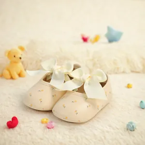 Detailansicht von Baby-Laufschuhen mit Blumenmuster und eleganten cremefarbenen Schleifen
