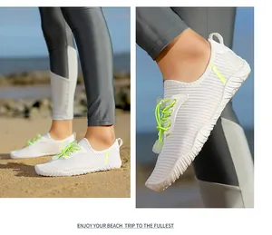 Close-up of white quick-dry water shoes with neon green elastic laces on beach scene.