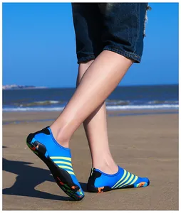 Detailopname van blauwe waterschoenen met gele strepen gedragen op een zonnig zandstrand