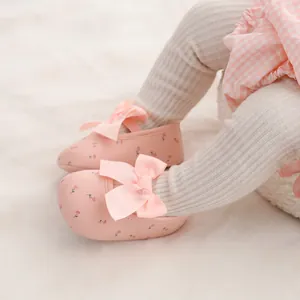 Detailansicht rosa Baby-Prinzessin-Schuhe mit einer großen Schleife und Blumenmuster