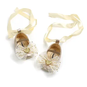 Detailansicht goldener Baby-Prinzessinenschuhe mit Tüllschleife und Satinbändern