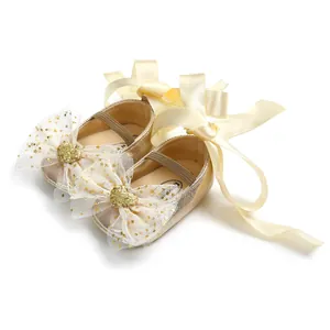 Detailsicht von Baby-Prinzessin-Schuhen mit Goldglitzer und cremefarbenen Schleifen