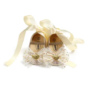 Detail von Baby-Prinzessin-Schuhen mit Satinbändern und funkelnden Herz-Tüllschleifen