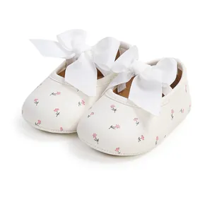 Detailansicht weißer Baby-Prinzessinenschuhe mit Blumenmuster und großer Schleife