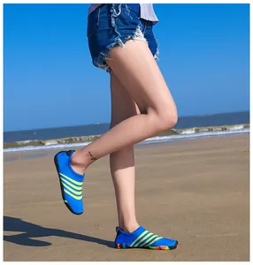 Detailweergave van blauwe blote voeten waterschoenen met gele strepen op het strand