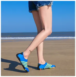 Zijaanzicht van blauw en geel gestreepte waterschoenen gedragen op een zonnig zandstrand
