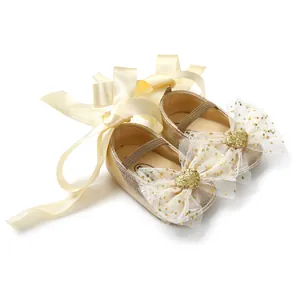 Detailansicht goldene Baby-Prinzessinenschuhe mit Glitzerschleife und Satinbändern