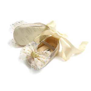 Detailansicht goldene Glitzer-Babyschuhe mit einer champagnerfarbenen Schleife