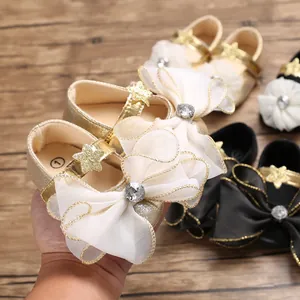 Detailed view of gold baby girl walking shoes with large white organza bows and stones