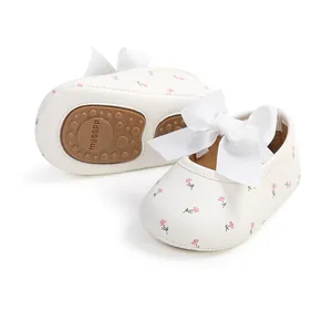 Detailansicht weißer Baby-Lauflernschuhe mit Blumendruck und großer weißer Schleife