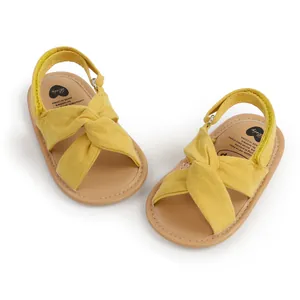 Vista superior de sandalias amarillas para bebé con diseño de nudo cruzado de tela