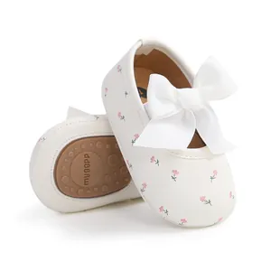 Detail eines weißen Lauflernschuhs für Babys mit rosa Blumendruck und großer Schleife