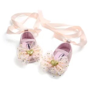 Detailaufnahme rosa Baby-Prinzessinnenschuhe mit Spitzenschleife und goldenem Herz