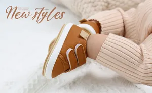 Close-up of a brown leather baby walking shoe with double velcro straps on a soft background.