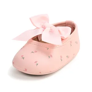 Nahaufnahme von rosa Baby-Prinzessinenschuhen mit großer Schleife und Blumenprint.