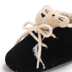 Detalle de zapato de bebé en terciopelo negro con oso de peluche y forro polar cálido.