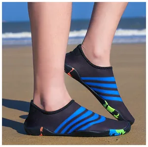 Detailopname van zwart en blauw gestreepte waterschoenen gedragen op een zandstrand