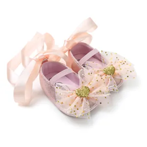 Detailaufnahme von eleganten rosa Glitzer-Babyschuhen mit Netzschleifen und Satinbändern