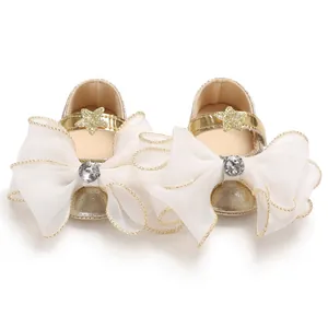 Close-up of elegant baby girl gold princess shoes with large white bows and rhinestone details