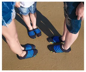Familie draagt bijpassende zwart-blauw gestreepte waterschoenen op een zonnig strand