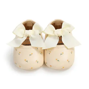 Nahaufnahme von beigen Baby-Prinzessinenschuhen mit großen cremefarbenen Schleifen und Blumen.