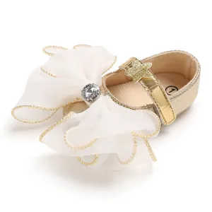 Detail view of golden baby girl princess shoe with large white chiffon bow