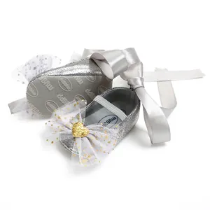 Detail der silbernen Glitzer-Babyschuhe mit Spitzenschleifen und langen Bändern