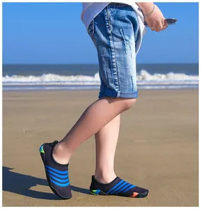 Detailopname van een kind met zwarte waterschoenen met blauwe strepen op een zonnig strand