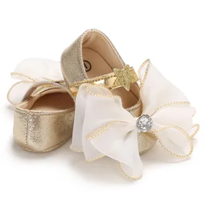 Detailed macro shot of infant girl gold princess shoes featuring large white organza bows