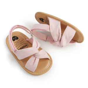 Detalle de sandalias rosas para bebé con correas cruzadas y textura de gamuza suave