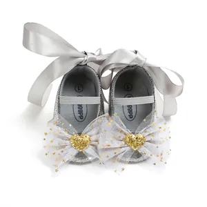 Detailansicht silberne Babyschuhe mit glitzernden Herz-Schleifen und Seidenbändern