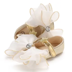 Detail of gold baby princess shoes with large organza bow and rhinestone center