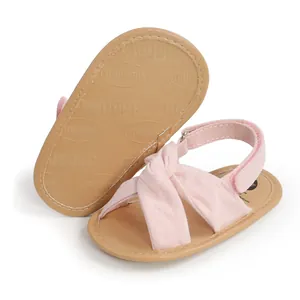 Primer plano de sandalias rosas para bebé con correas cruzadas y suela antideslizante.