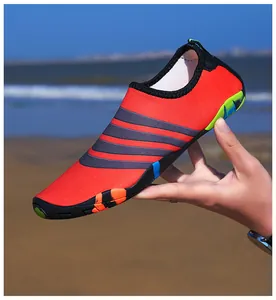 Detailopname van een flexibele oranje waterschoen tegen een strandachtergrond
