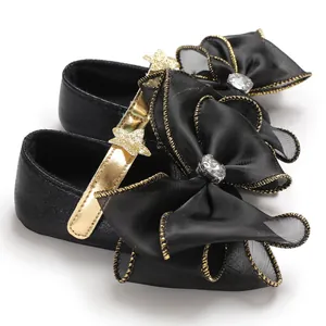 Detailed view of black infant princess shoes with large mesh bows and gold star straps